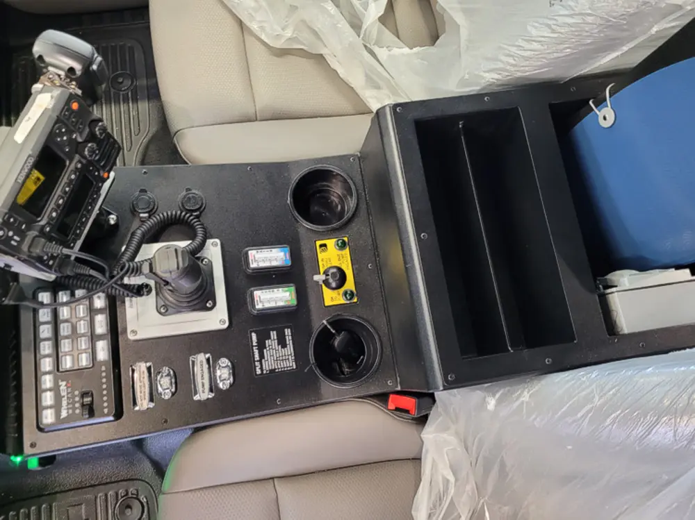 Exterior view of small fire truck showing cab, body compartments, and wheel/tire area.