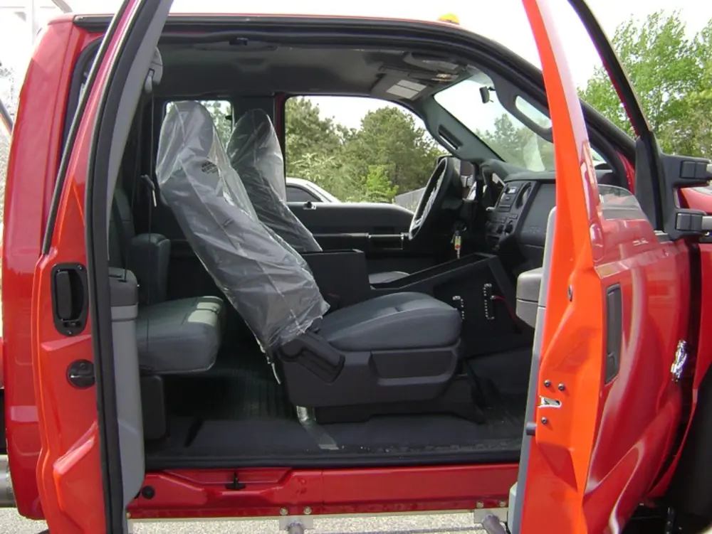 Exterior view of small fire truck showing cab, body compartments, and wheel/tire area.