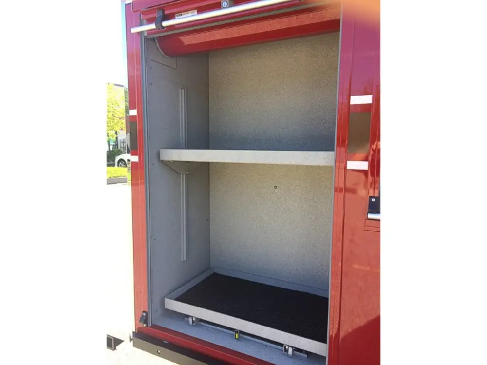 Exterior view of small fire truck showing cab, body compartments, and wheel/tire area.