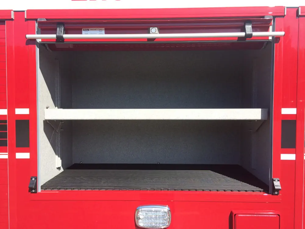 Exterior view of small fire truck showing cab, body compartments, and wheel/tire area.