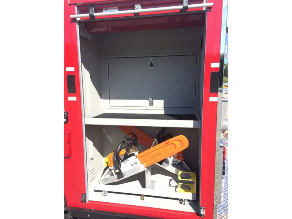 Exterior view of small fire truck showing cab, body compartments, and wheel/tire area.