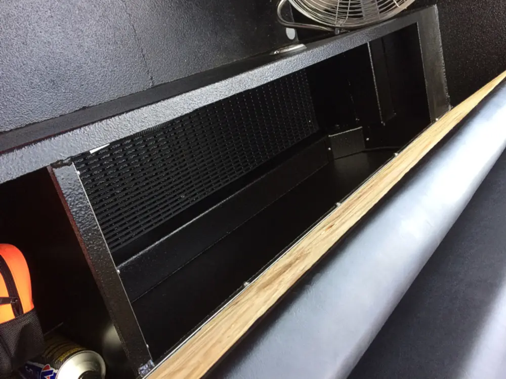 Exterior view of small fire truck showing cab, body compartments, and wheel/tire area.