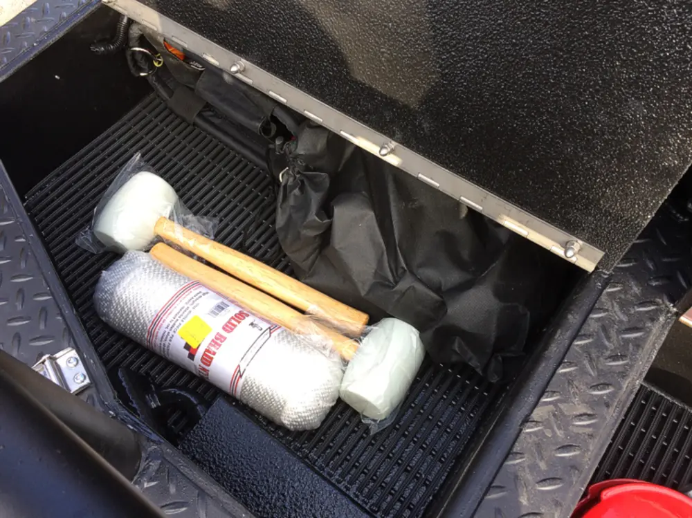 Exterior view of small fire truck showing cab, body compartments, and wheel/tire area.