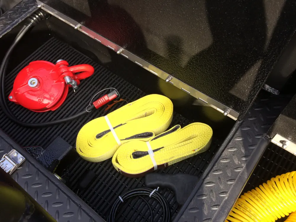 Exterior view of small fire truck showing cab, body compartments, and wheel/tire area.