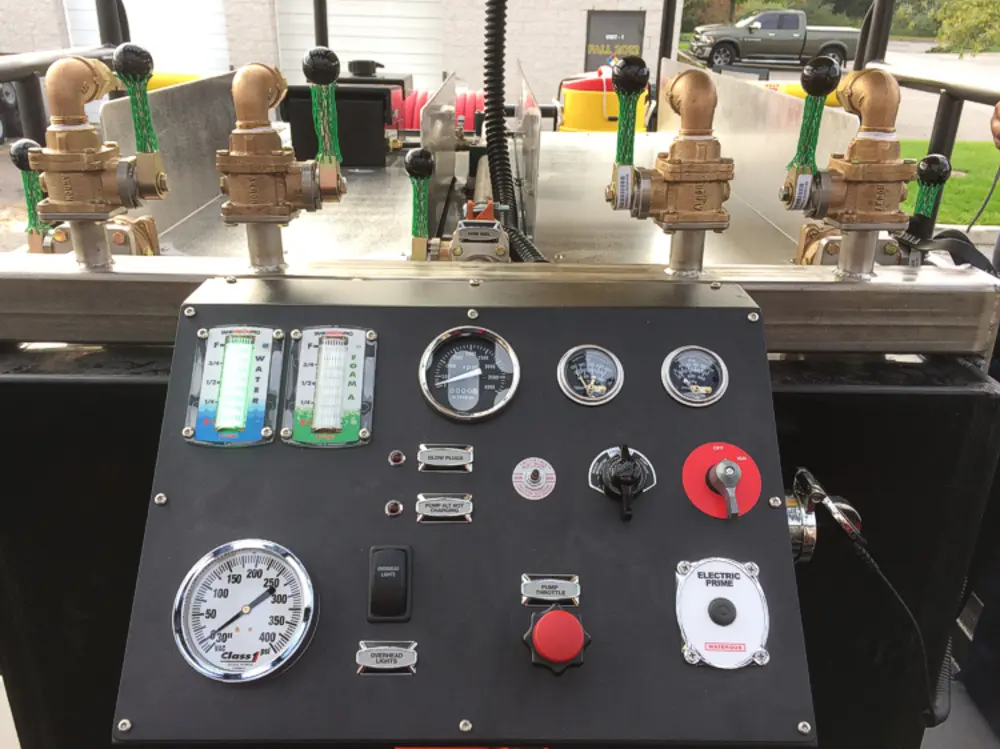 Exterior view of small fire truck showing cab, body compartments, and wheel/tire area.