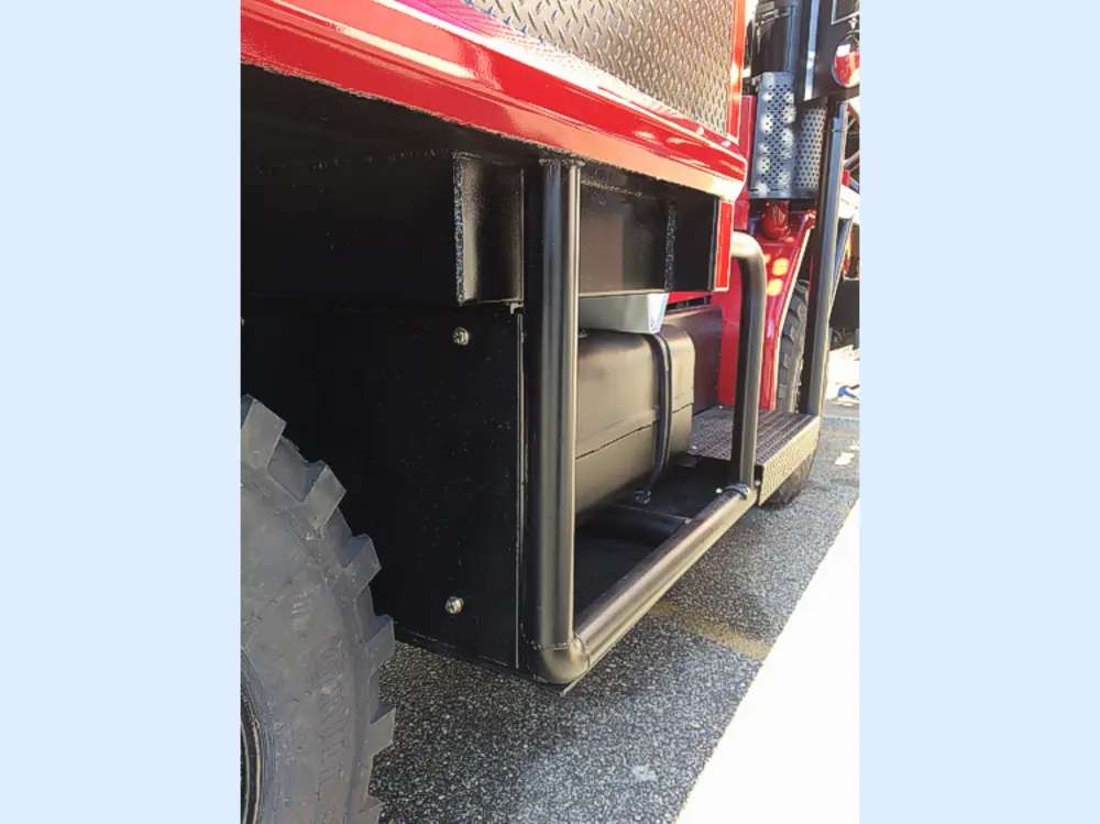 Exterior view of small fire truck showing cab, body compartments, and wheel/tire area.