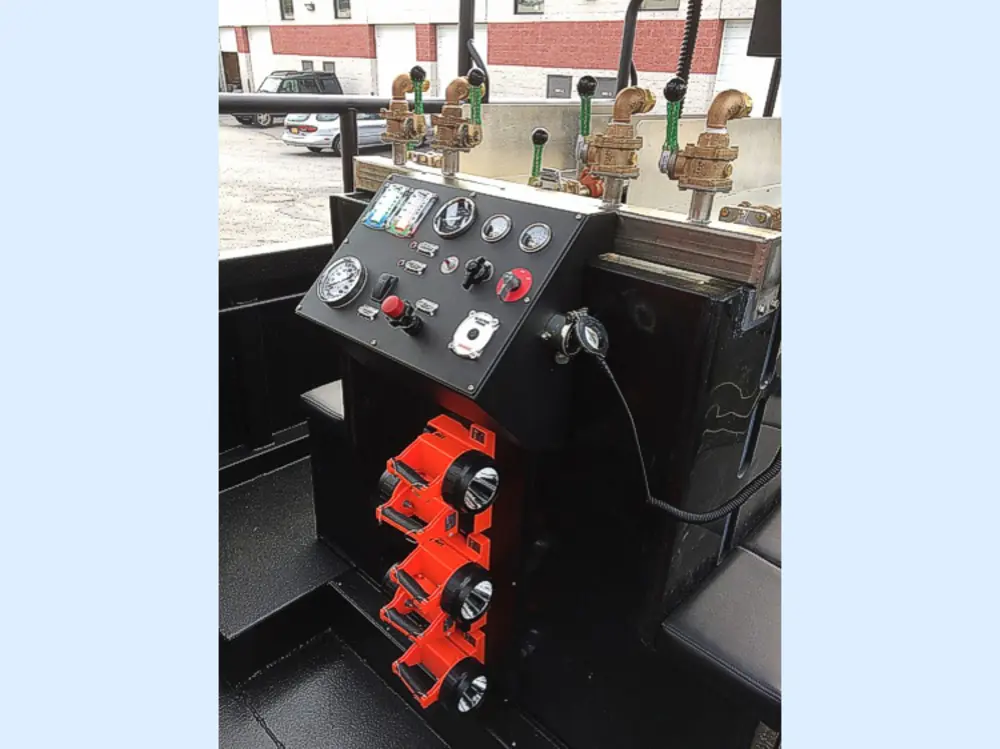 Exterior view of small fire truck showing cab, body compartments, and wheel/tire area.