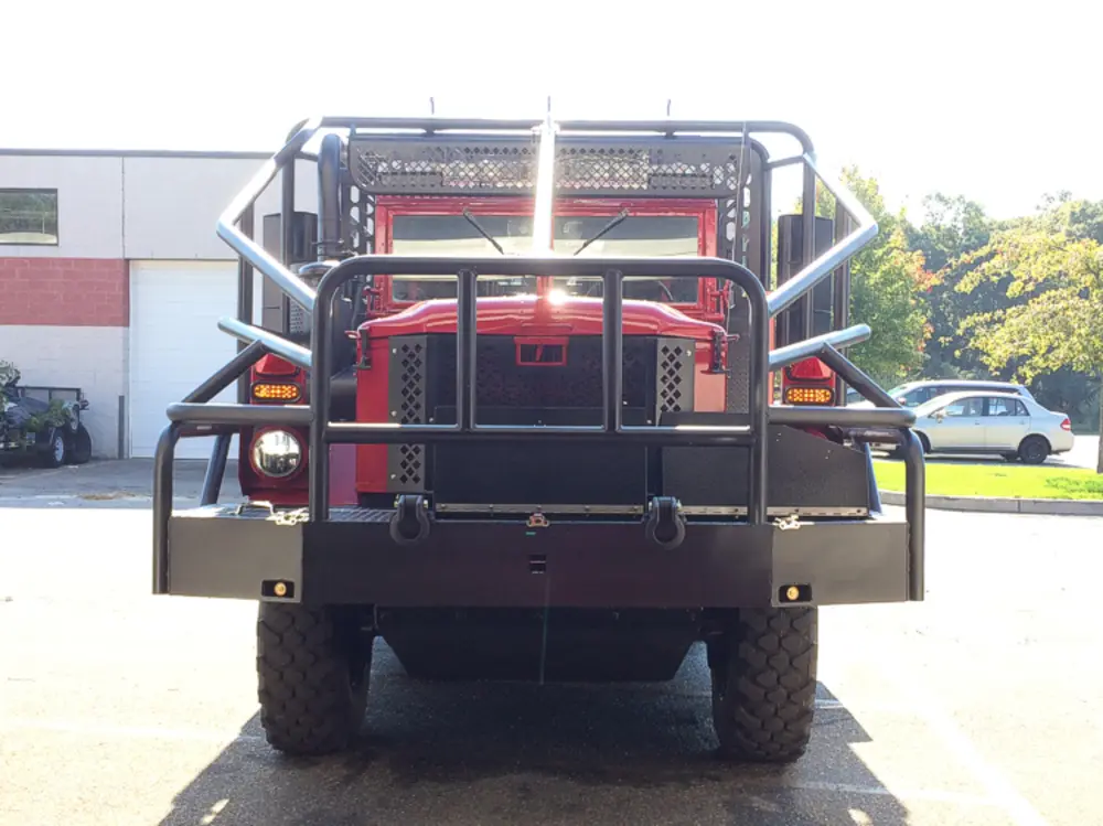 Exterior view of small fire truck showing cab, body compartments, and wheel/tire area.