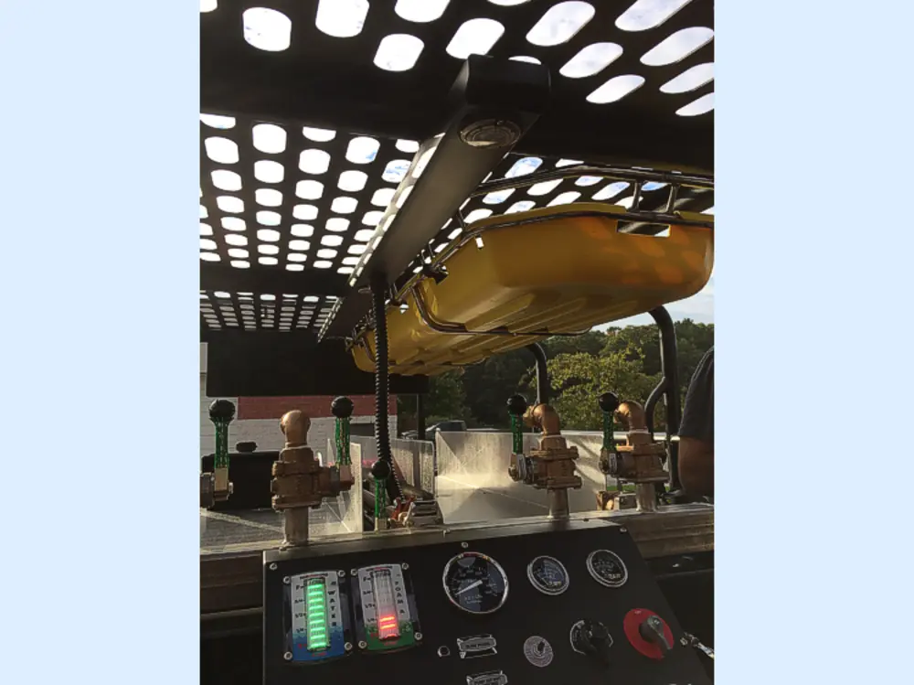 Exterior view of small fire truck showing cab, body compartments, and wheel/tire area.