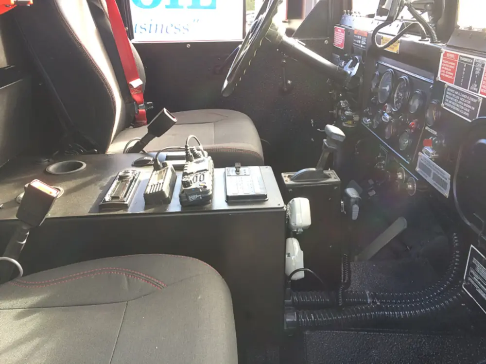 Exterior view of small fire truck showing cab, body compartments, and wheel/tire area.