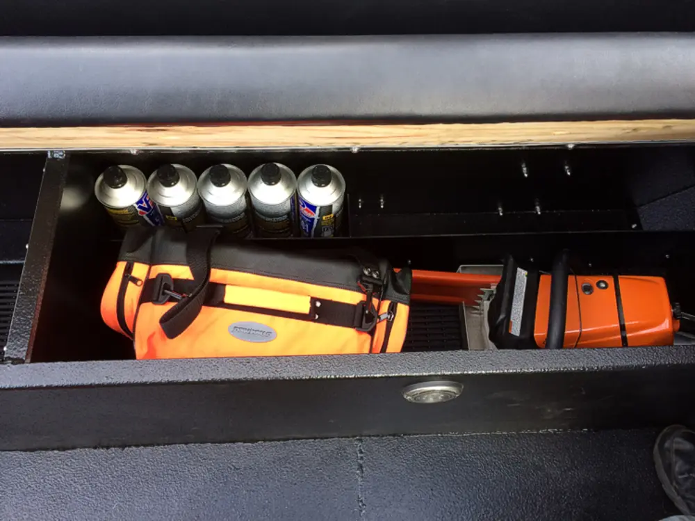 Exterior view of small fire truck showing cab, body compartments, and wheel/tire area.