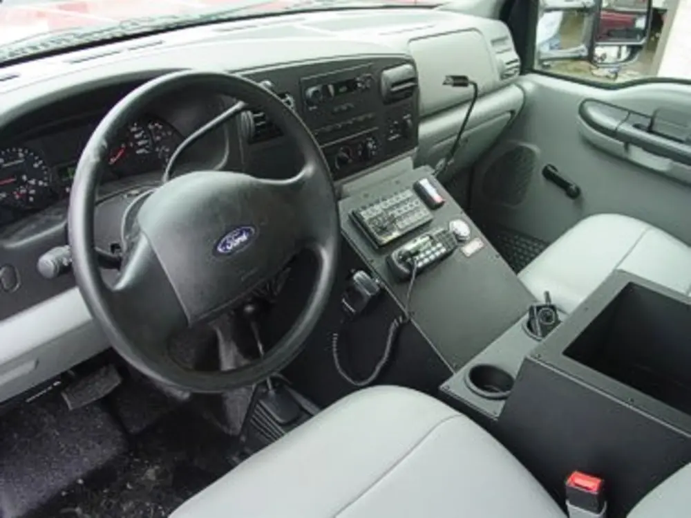 Exterior view of small fire truck showing cab, body compartments, and wheel/tire area.