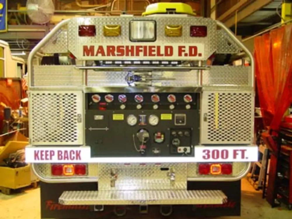 Exterior view of small fire truck showing cab, body compartments, and wheel/tire area.