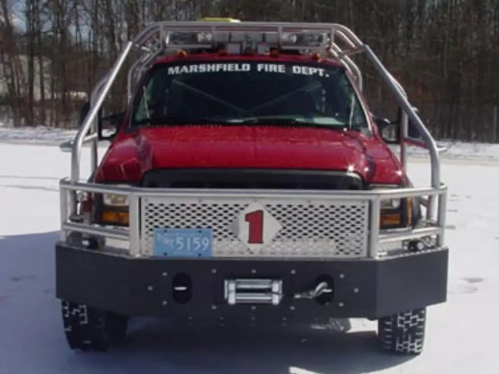 Exterior view of small fire truck showing cab, body compartments, and wheel/tire area.