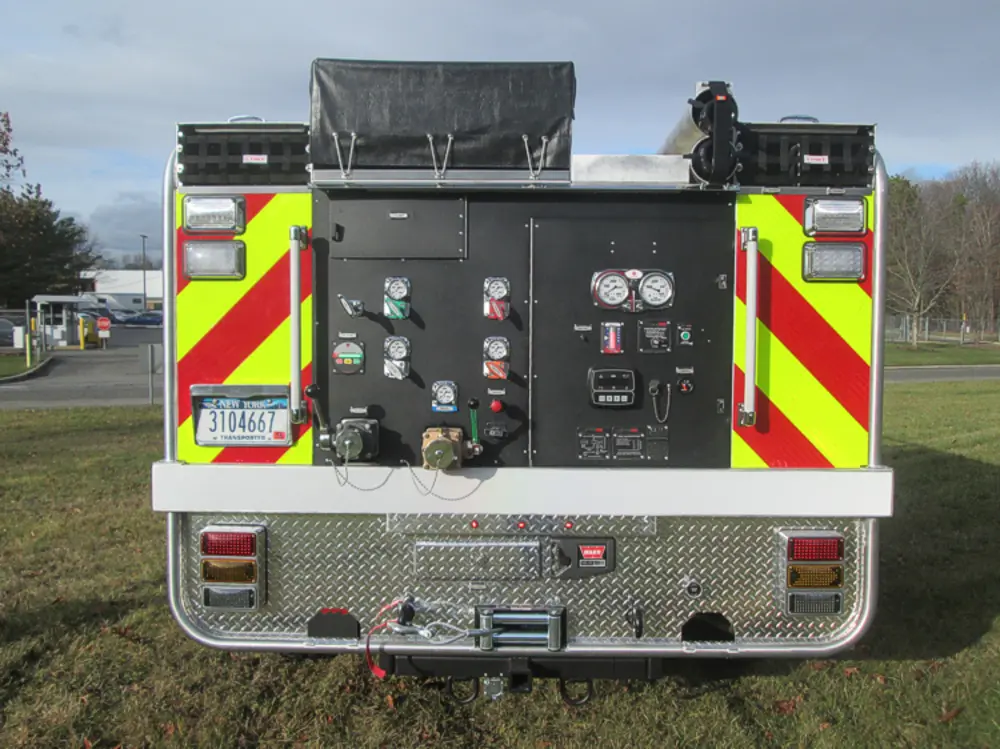 Exterior view of small fire truck showing cab, body compartments, and wheel/tire area.