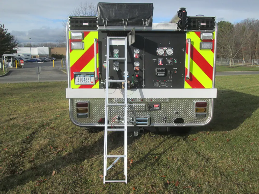 Exterior view of small fire truck showing cab, body compartments, and wheel/tire area.