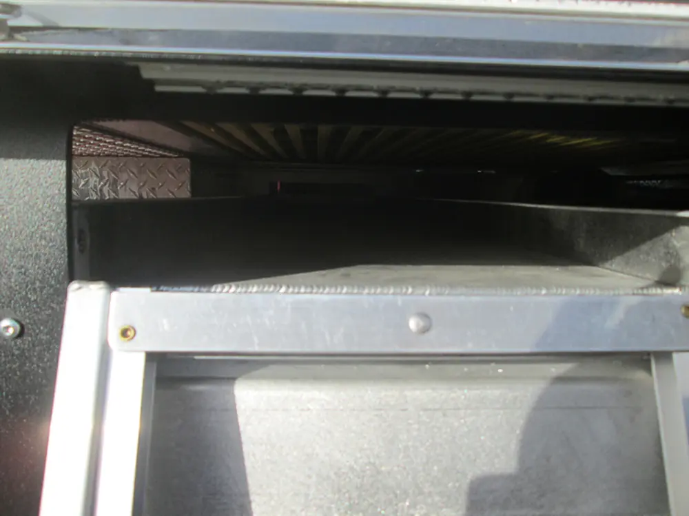 Exterior view of small fire truck showing cab, body compartments, and wheel/tire area.