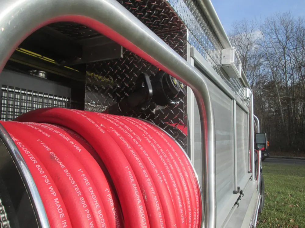 Exterior view of small fire truck showing cab, body compartments, and wheel/tire area.
