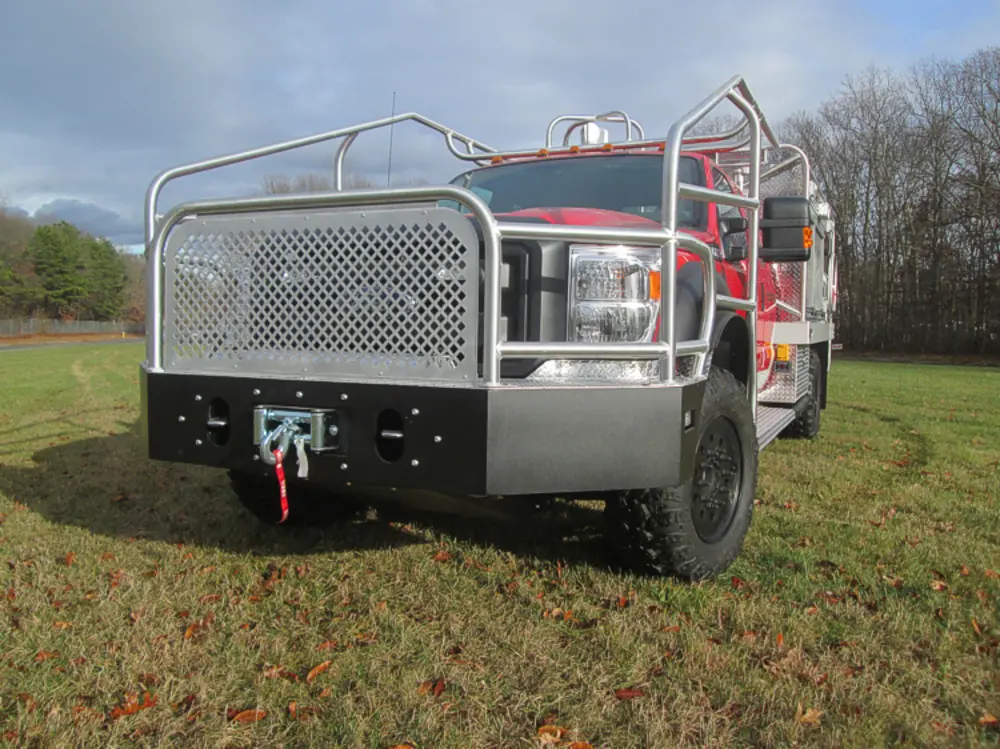 Exterior view of small fire truck showing cab, body compartments, and wheel/tire area.