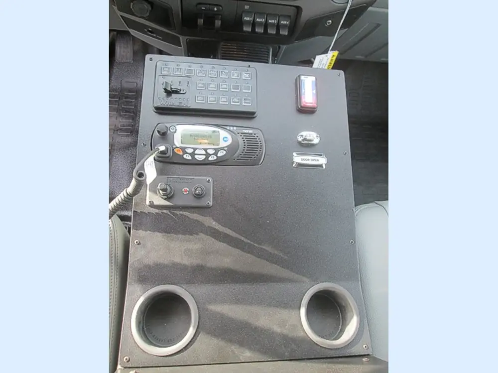 Exterior view of small fire truck showing cab, body compartments, and wheel/tire area.