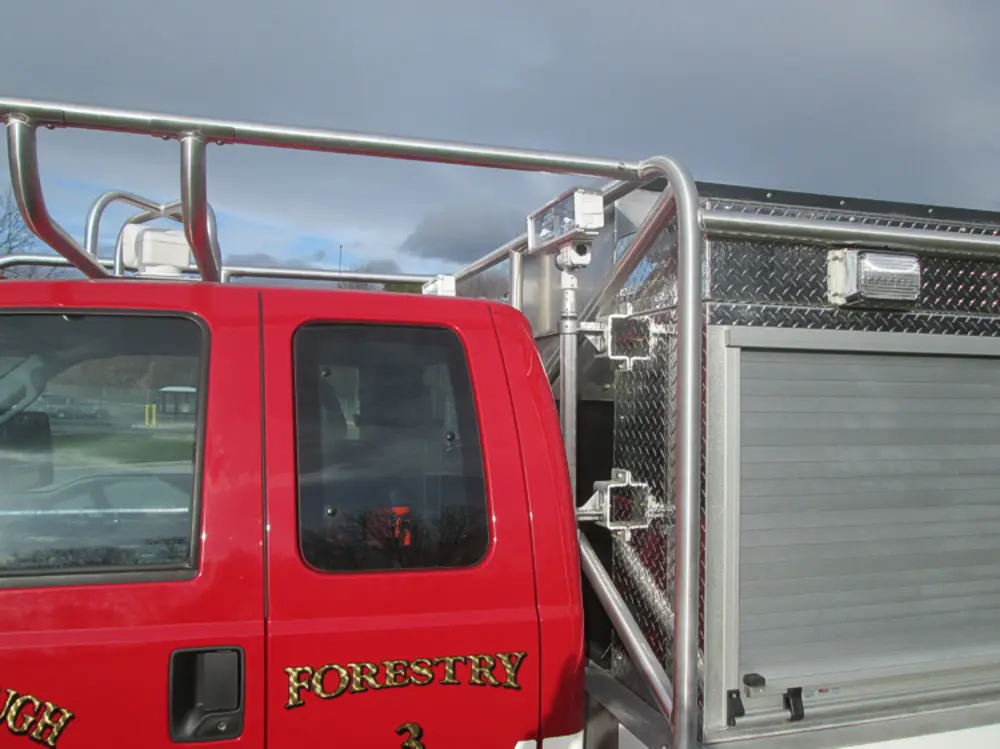 Exterior view of small fire truck showing cab, body compartments, and wheel/tire area.