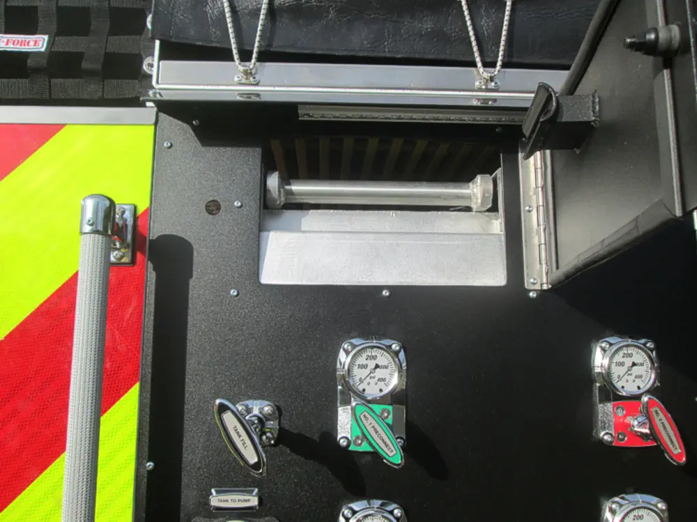 Exterior view of small fire truck showing cab, body compartments, and wheel/tire area.