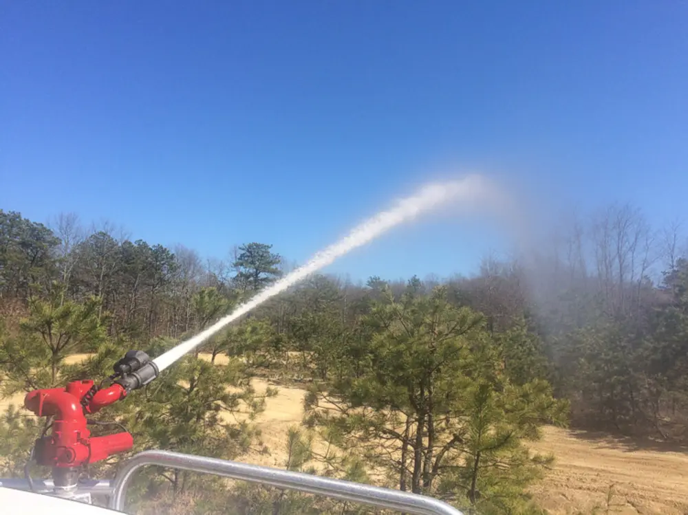 Exterior view of small fire truck showing cab, body compartments, and wheel/tire area.