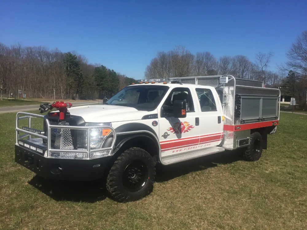 Exterior view of small fire truck showing cab, body compartments, and wheel/tire area.