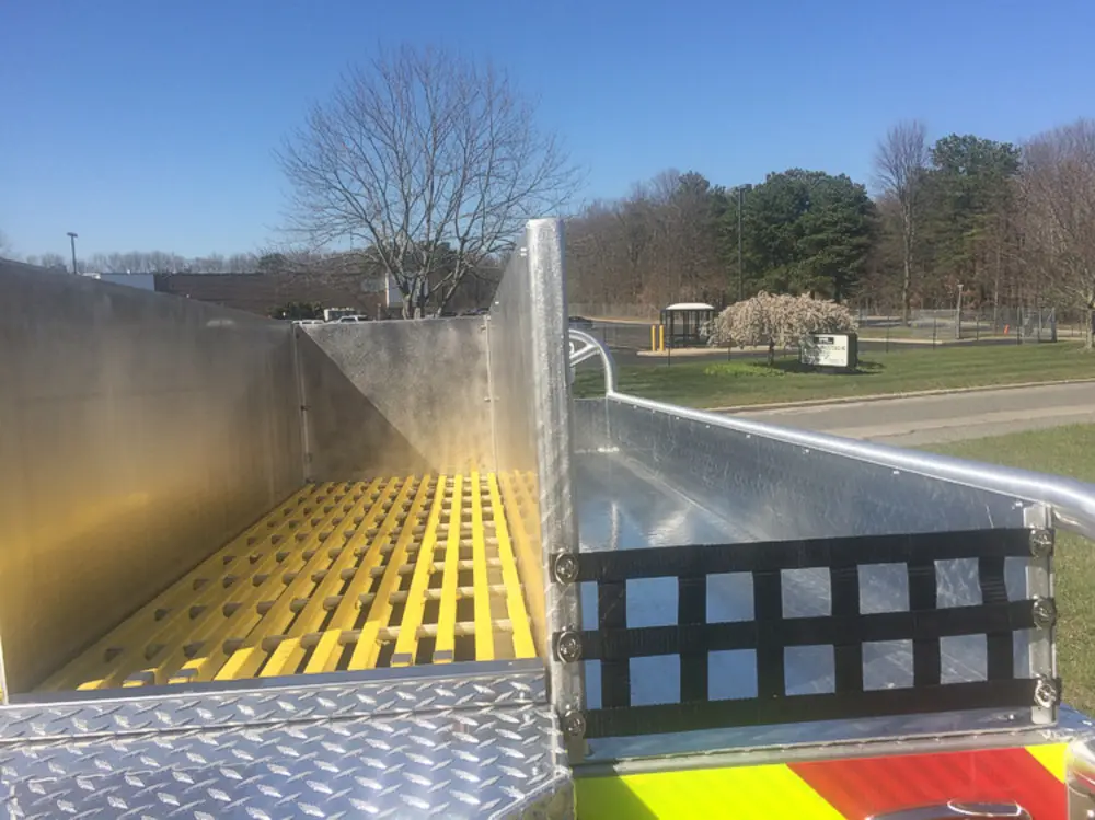 Exterior view of small fire truck showing cab, body compartments, and wheel/tire area.