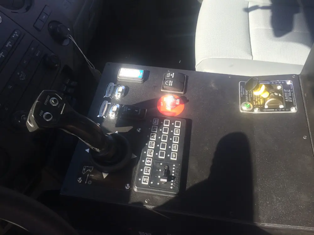 Exterior view of small fire truck showing cab, body compartments, and wheel/tire area.