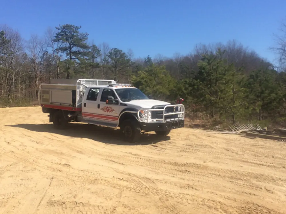 Exterior view of small fire truck showing cab, body compartments, and wheel/tire area.