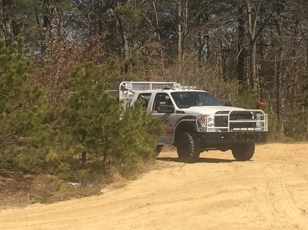 Exterior view of small fire truck showing cab, body compartments, and wheel/tire area.