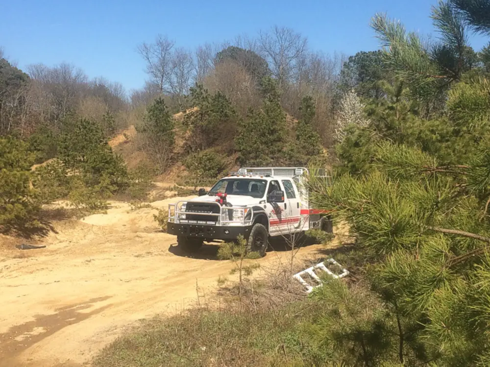 Exterior view of small fire truck showing cab, body compartments, and wheel/tire area.