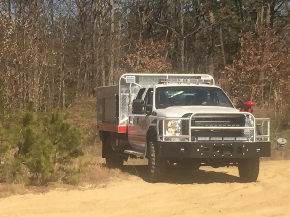 Exterior view of small fire truck showing cab, body compartments, and wheel/tire area.