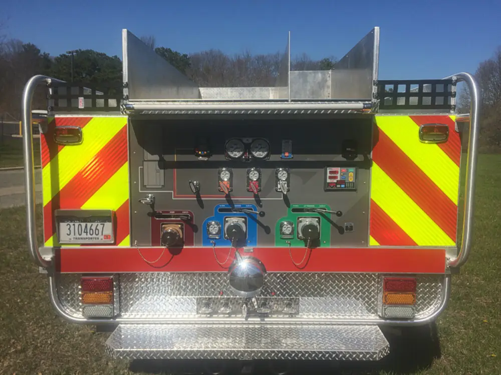 Exterior view of small fire truck showing cab, body compartments, and wheel/tire area.