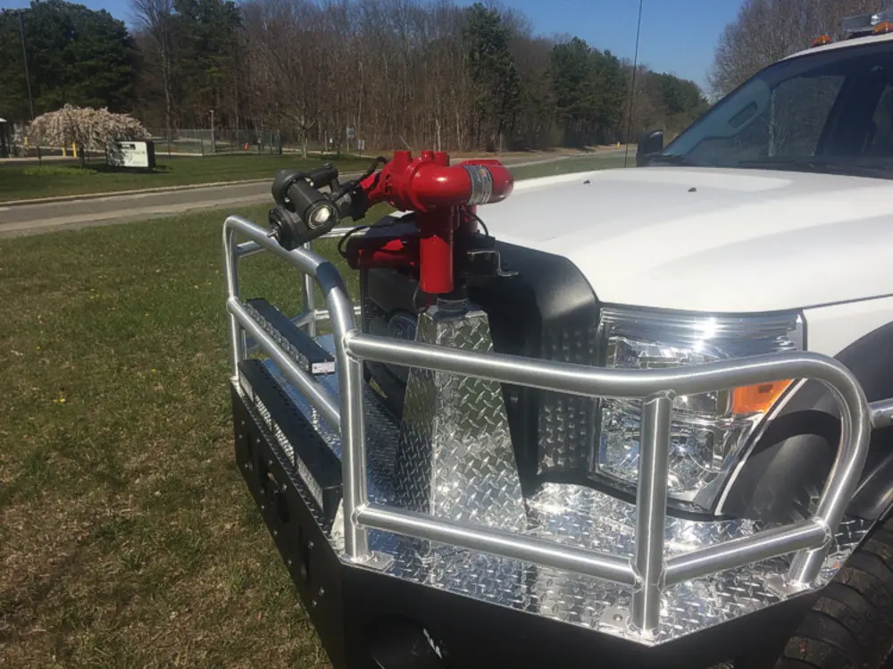 Exterior view of small fire truck showing cab, body compartments, and wheel/tire area.
