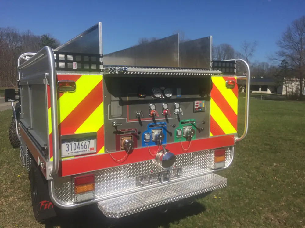 Exterior view of small fire truck showing cab, body compartments, and wheel/tire area.