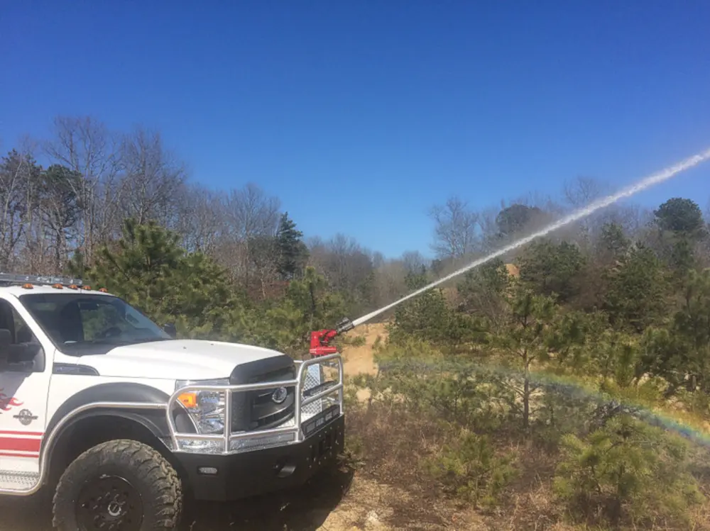 Exterior view of small fire truck showing cab, body compartments, and wheel/tire area.