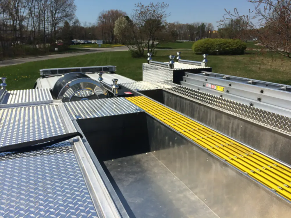 Exterior view of small fire truck showing cab, body compartments, and wheel/tire area.