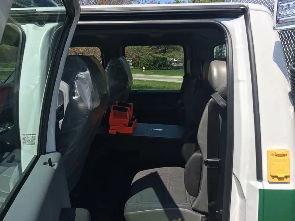 Exterior view of small fire truck showing cab, body compartments, and wheel/tire area.