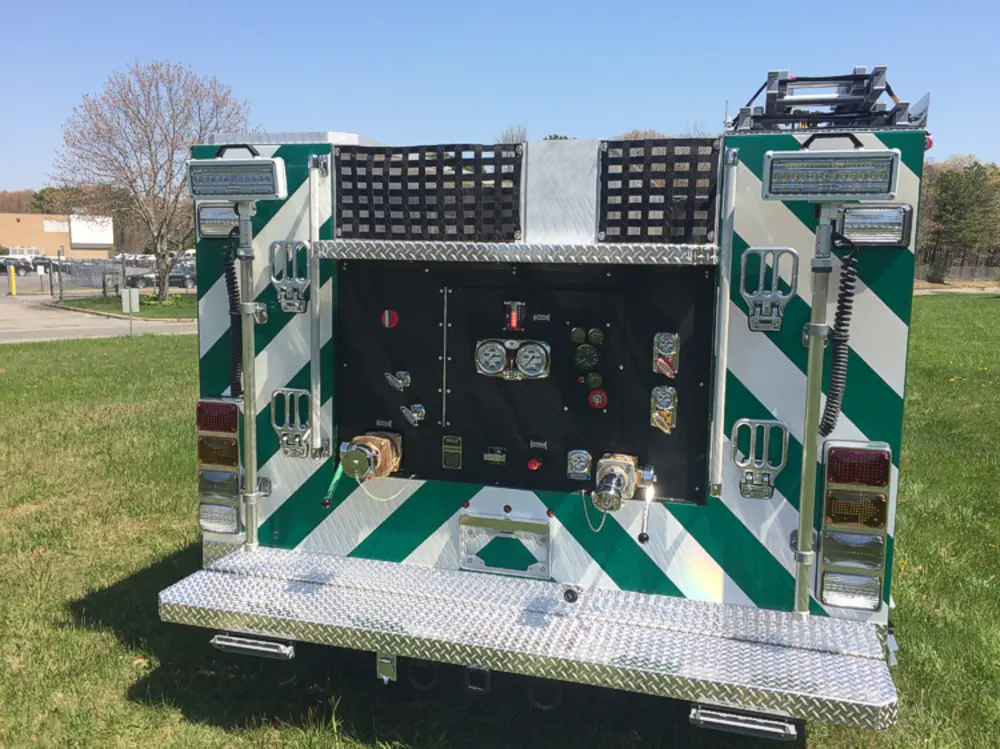 Exterior view of small fire truck showing cab, body compartments, and wheel/tire area.