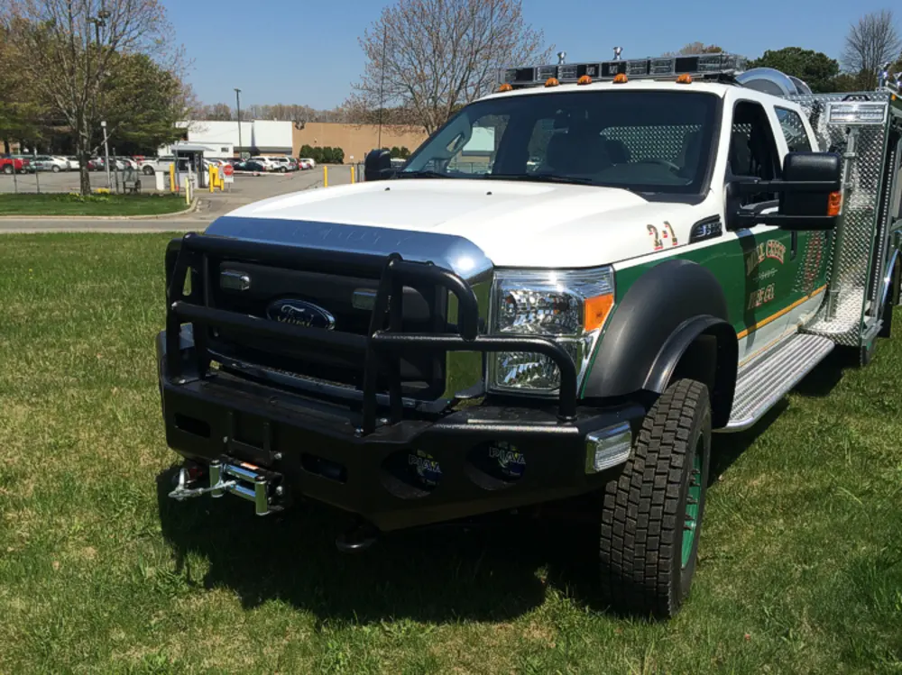 Exterior view of small fire truck showing cab, body compartments, and wheel/tire area.