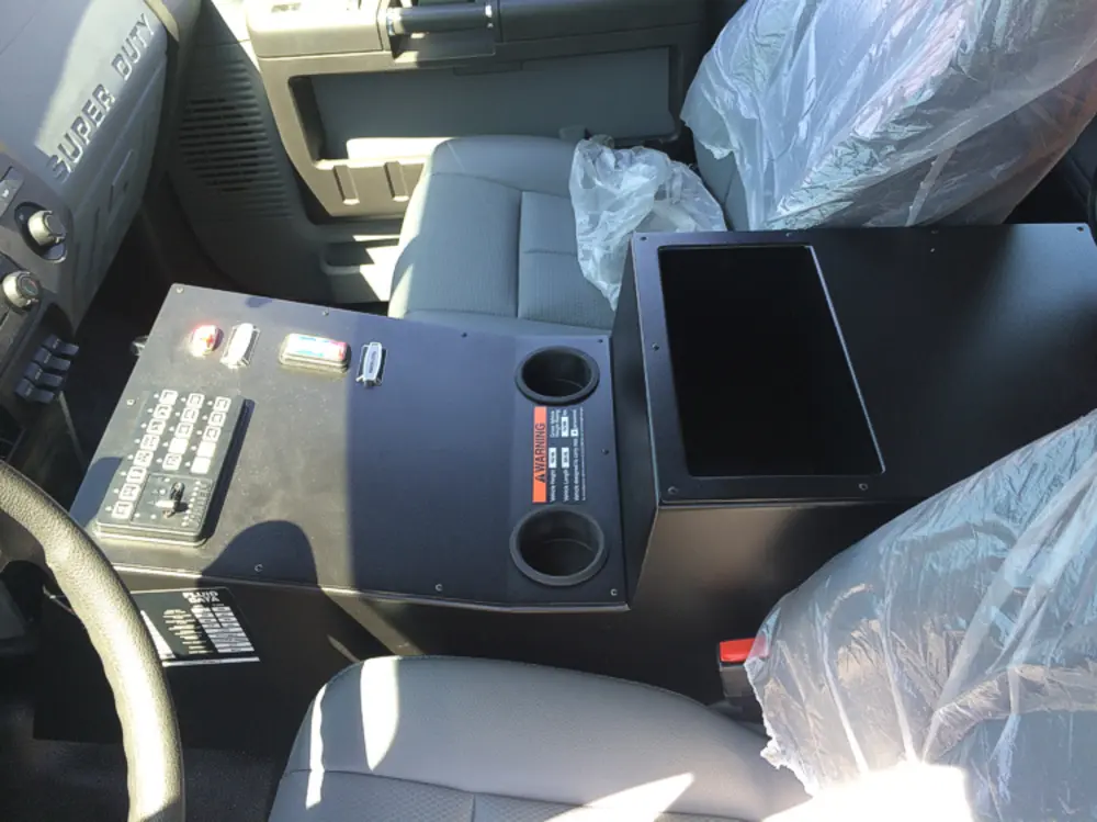 Exterior view of small fire truck showing cab, body compartments, and wheel/tire area.