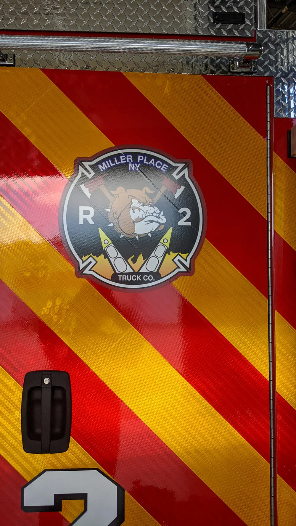 Exterior view of small fire truck showing cab, body compartments, and wheel/tire area.