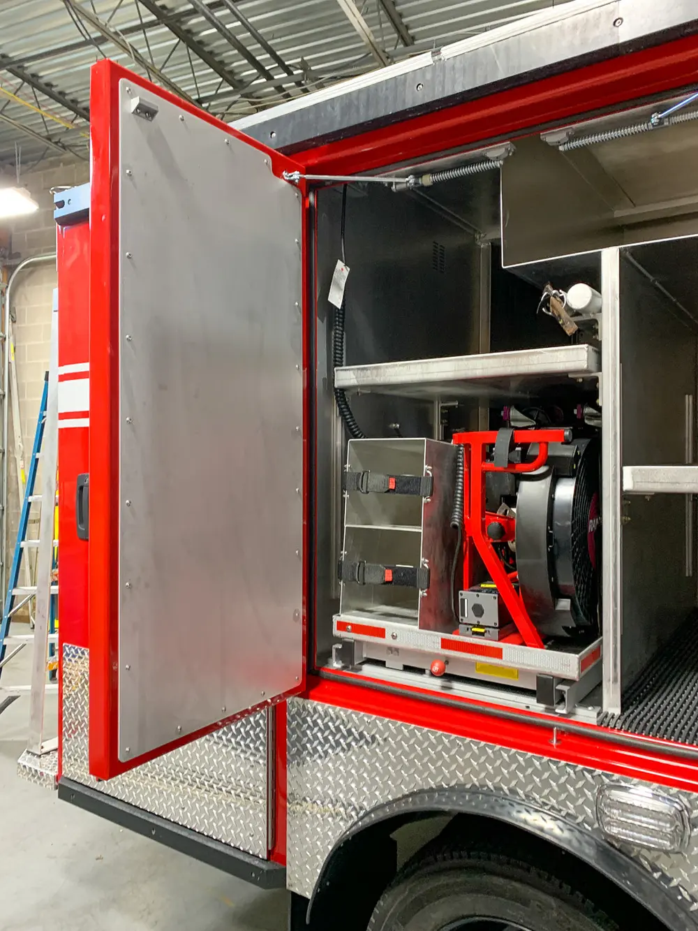 Exterior view of small fire truck showing cab, body compartments, and wheel/tire area.