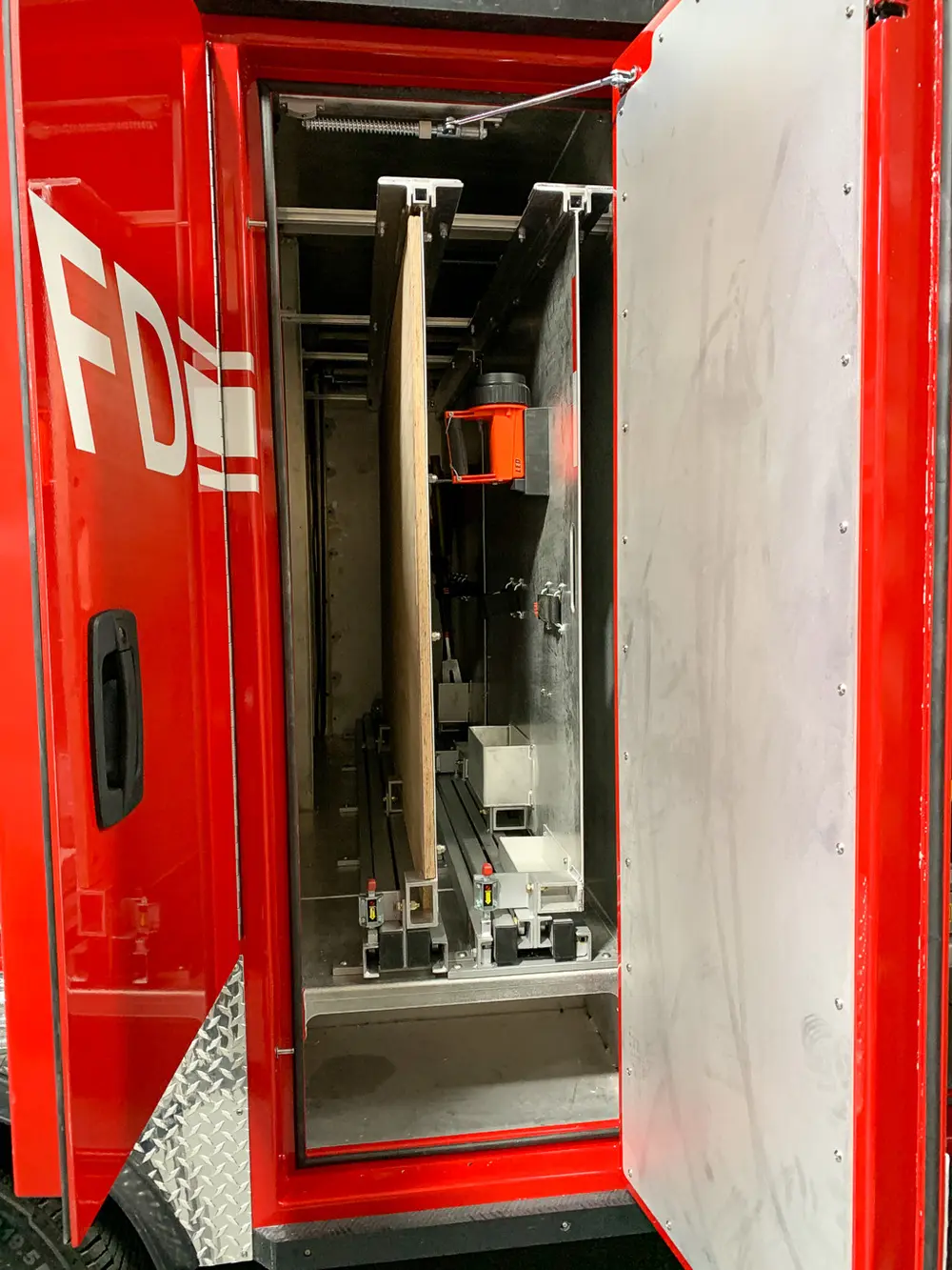 Exterior view of small fire truck showing cab, body compartments, and wheel/tire area.