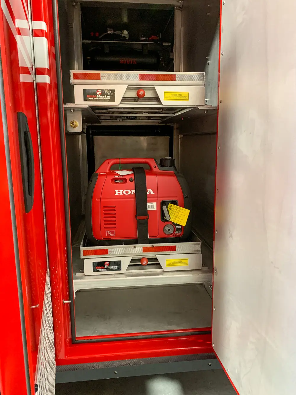 Exterior view of small fire truck showing cab, body compartments, and wheel/tire area.