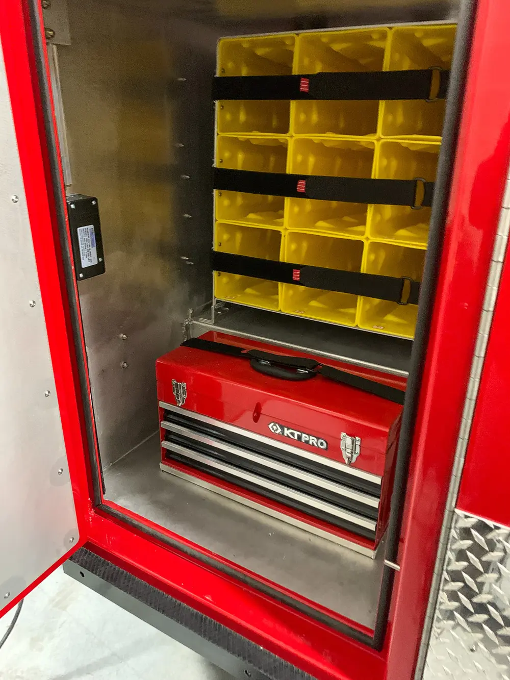 Exterior view of small fire truck showing cab, body compartments, and wheel/tire area.