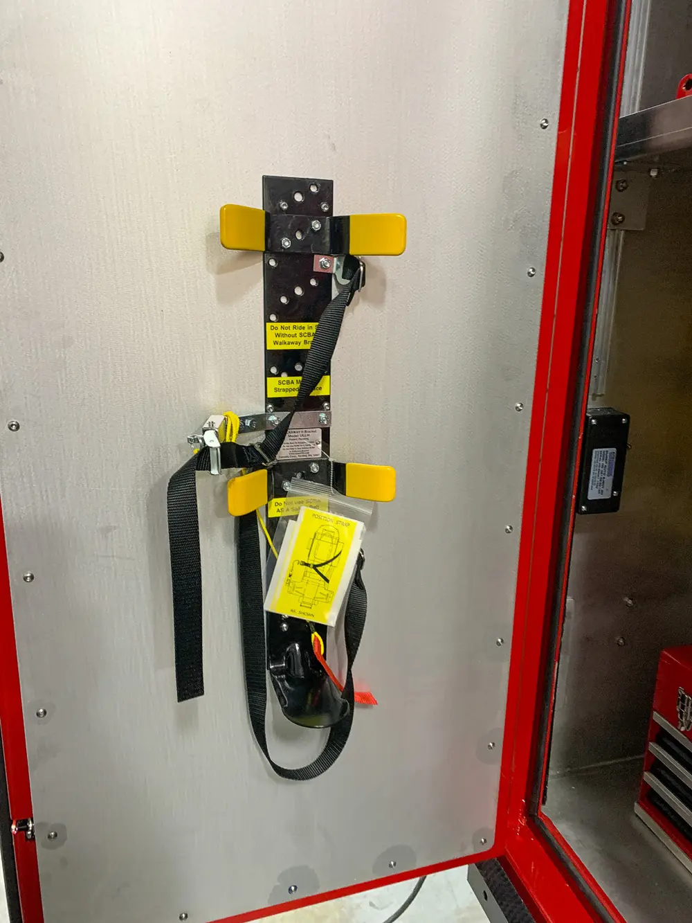 Exterior view of small fire truck showing cab, body compartments, and wheel/tire area.