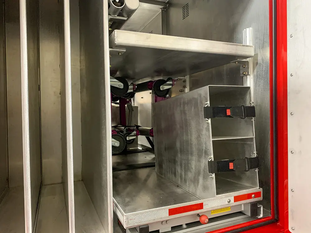 Exterior view of small fire truck showing cab, body compartments, and wheel/tire area.